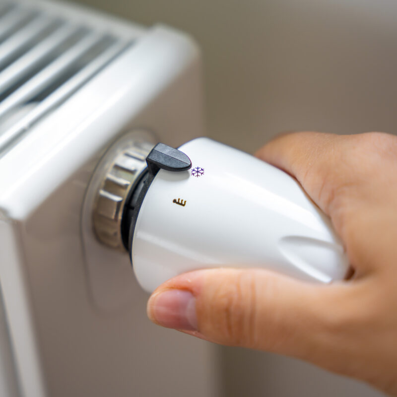 A woman's hand turns the battery heating knob. Heating in an apartment, at home. Heating prices.